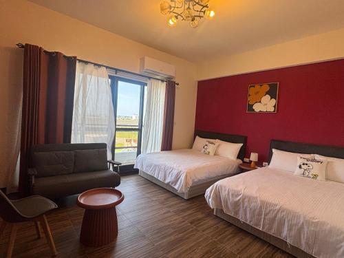 a hotel room with two beds and a chair and a window at Mian Bao Homestay in Magong