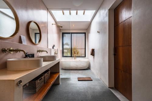 a bathroom with two sinks and a bath tub at Botanique Villa & Studio in Tanah Lot