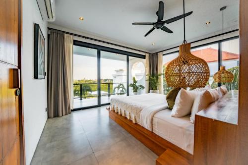 a bedroom with a bed and a large window at Botanique Villa & Studio in Tanah Lot