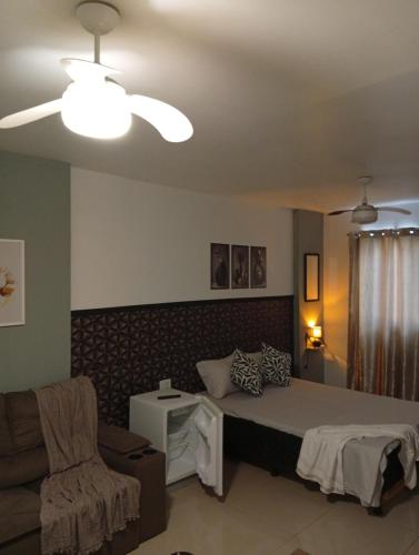 a bedroom with a bed and a couch and a ceiling fan at Studio Premium Trianon Centro in Campos dos Goytacazes