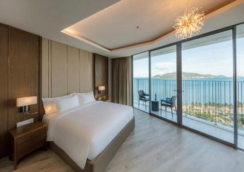 a bedroom with a large white bed and a large window at Panorama Blue Beach Nha Trang in Nha Trang