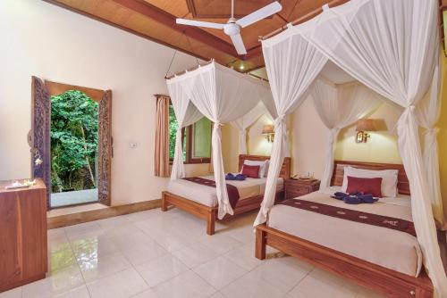 a bedroom with two beds with mosquito nets at Nick's Pension in Ubud