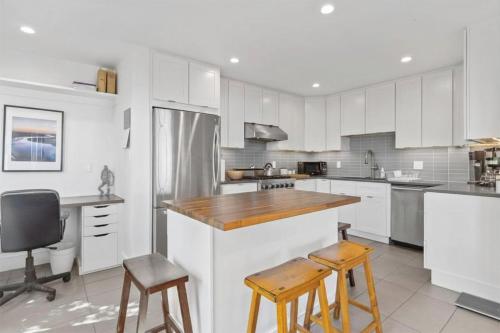 a kitchen with white cabinets and wooden counter stools at Stunning Views by the Bay 2BR in Brisbane