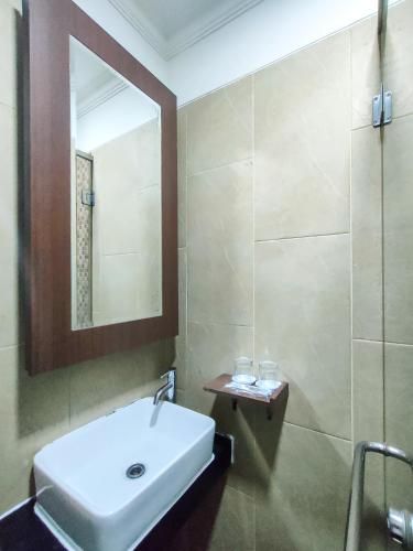 a bathroom with a white sink and a mirror at KAWANA HOTEL in Kampungdurian
