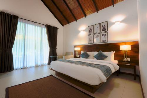 a bedroom with a large bed and a large window at Uppuveli Beach by DSK in Trincomalee