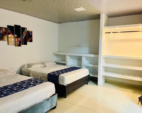 a bedroom with two beds and a desk and shelves at Hotel Roy in Santa Marta