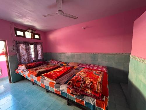 a bed in a room with a pink wall at Omji Ashram - Tapovan Kuti in Uttarkāshi