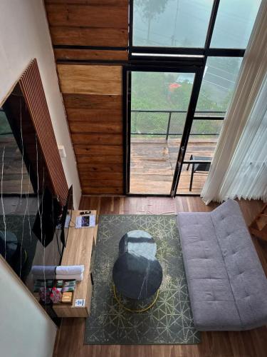 a living room with a couch and a large window at Villa Dieng Sikapuk Hill Superior Cabin in Kejajar