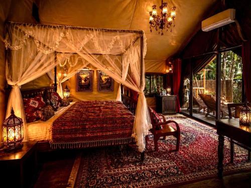 a bedroom with a canopy bed and a chandelier at Chateau Orientale Resort in Luang Prabang