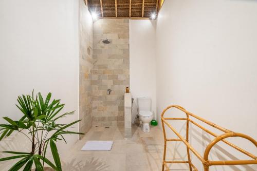 a bathroom with a toilet and a plant at Villa Anak Ikan in Gili Islands