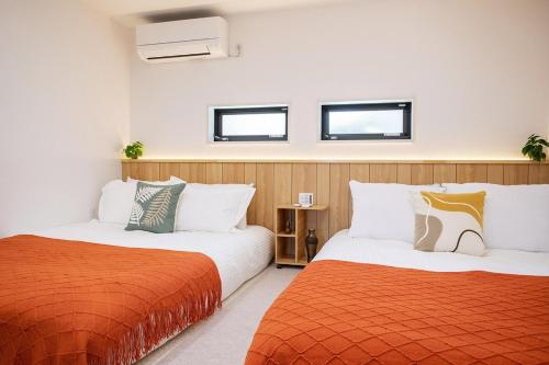 two beds with orange and white sheets in a room at Lucky Today in Osaka