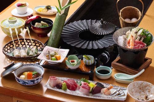 a table topped with plates of sushi and other food at 夫婦露天風呂の宿吟松 in Ibusuki