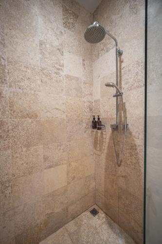 a shower with a shower head in a bathroom at Room & Vespa 4 - Central Seminyak Near Beach in Seminyak