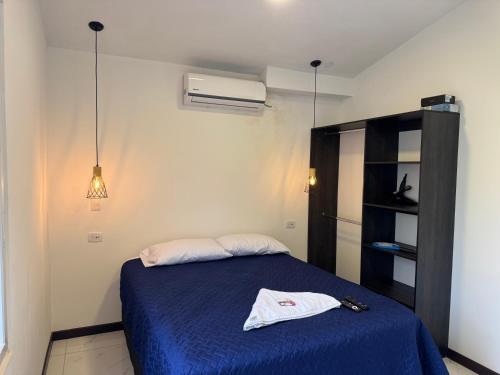 a bedroom with a bed with a blue blanket and a fan at Casa Escondida in San Felipe