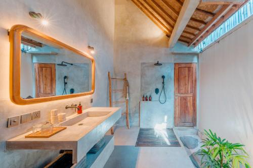 a bathroom with a sink and a mirror and a shower at Villa Manouch in Nusa Lembongan