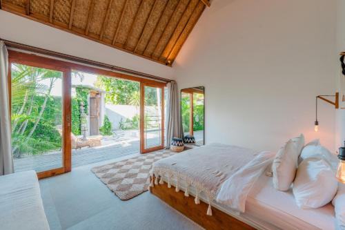 a bedroom with a bed and a large window at Villa Manouch in Nusa Lembongan