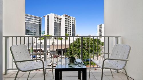two chairs and a table on a balcony with buildings at Mantra Hotel Room in Cairns
