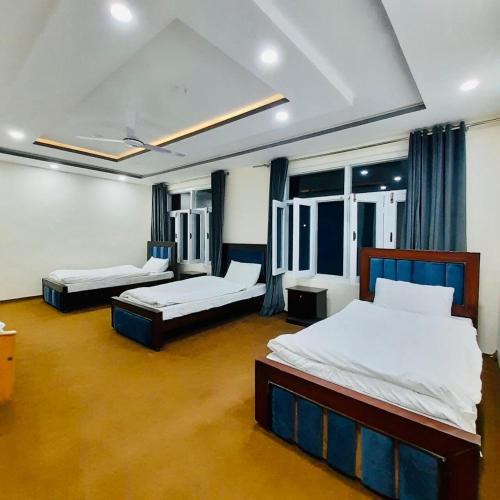 a room with two beds and two windows at Alpen Hotel Skardu in Skardu