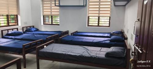 three beds in a room with blue sheets at Dreamers Lounge in Trichūr