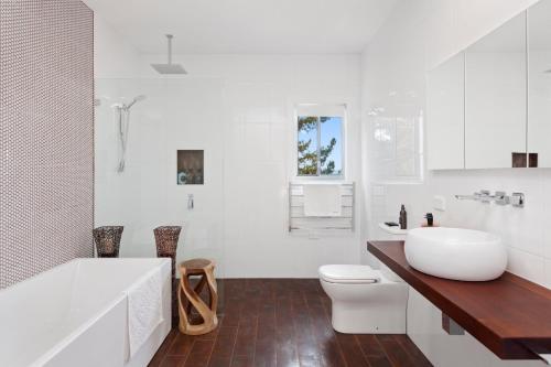 a bathroom with a tub and a toilet and a sink at The View @ Ulandi in Lowther