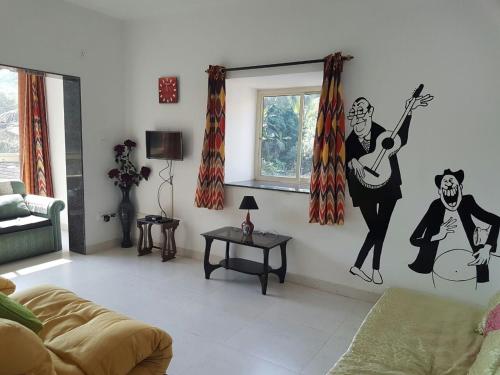 a living room with a mural of a woman playing a guitar at Ocean Shores Hospitality in Candolim