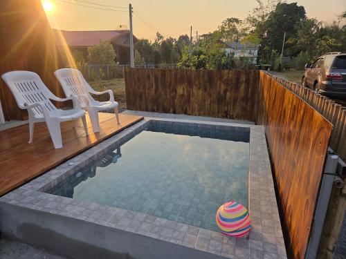 a swimming pool with two chairs and a ball in it at CK Family in Nakhon Nayok