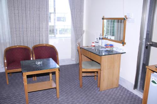 a room with a desk and chairs and a mirror at Quality Inn Dhaka in Dhaka