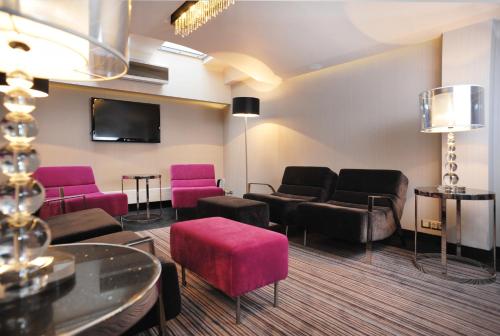 a waiting room with pink furniture and a flat screen tv at Hotel 3 Trio in Białystok