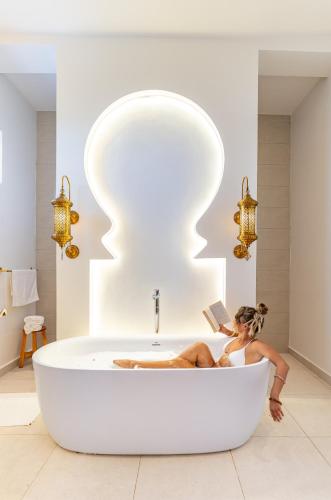 a woman laying in a bath tub reading a book at Halisi Villas in Nungwi