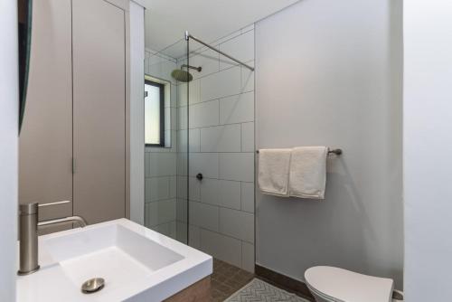 a white bathroom with a sink and a shower at Stylish Studio with Ocean Views at Wavescapes in Muizenberg