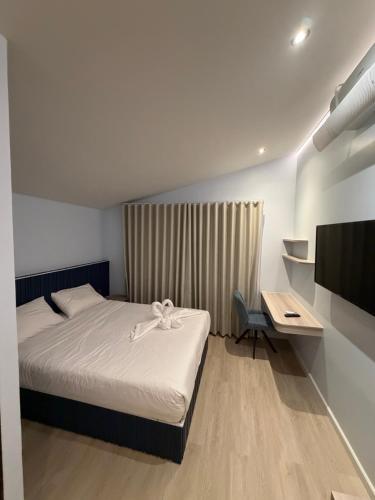 a bedroom with a bed and a desk and a television at ของขวัญรีสอร์ท in Ban Khlong Ai Kok
