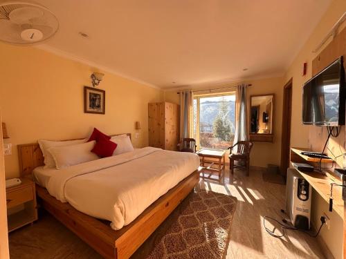 a bedroom with a large bed and a television at Highfield Villa in Kanatal