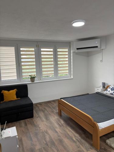 a bedroom with a bed and a couch and windows at Apartman Ljiljan in Sanski most