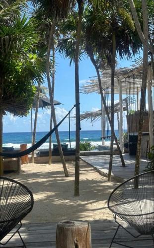 a hammock on a beach with palm trees and the ocean at TULUM Beachfront Villa Kiin in Tulum