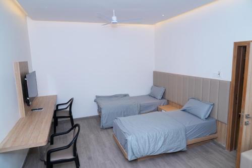 a room with two beds and a table and chairs at Hotel Avani Grand in Zahirābād