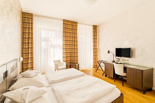 a hotel room with two beds and a desk at Hotel Trinity in Olomouc
