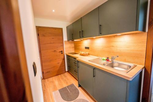 eine kleine Küche mit Spüle und Holzschränken in der Unterkunft Schulerhof in Oberau