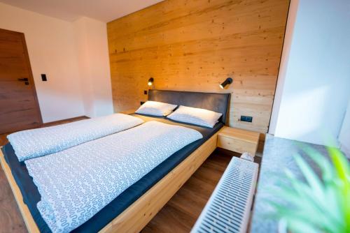 ein Schlafzimmer mit einem Bett und einer Holzwand in der Unterkunft Schulerhof in Oberau