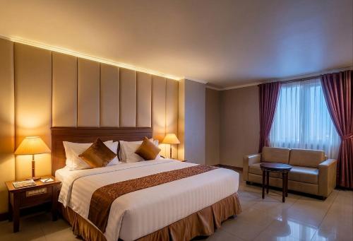 a hotel room with a large bed and a chair at Olympic Hotel Jakarta in Jakarta