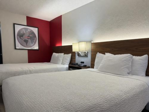 two beds in a hotel room with red walls at Ramada by Wyndham Harrisonburg in Harrisonburg