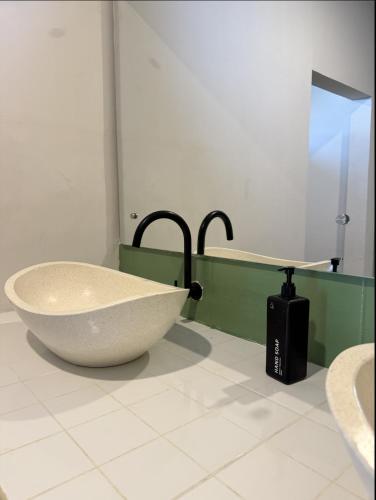 a bathroom with a large white tub and a sink at Nira Hostel Kuta Lombok in Kuta Lombok
