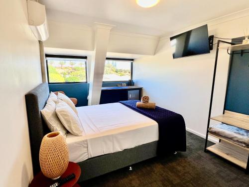 a small bedroom with a bed and two windows at Sails Motel Geraldton in Geraldton