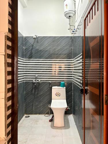 a bathroom with a toilet and a black and white wall at Mountain View Terrace Room Upper Tapovan in Rishīkesh