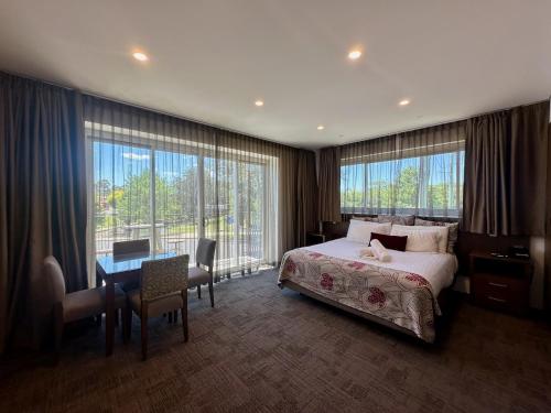 a hotel room with a bed and a desk and window at Young Federation Motor Inn and Services Club in Young