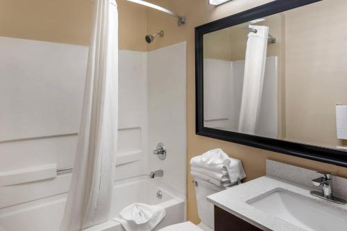 a bathroom with a tub and a sink and a mirror at Quality Inn Overland Park Kansas City in Overland Park