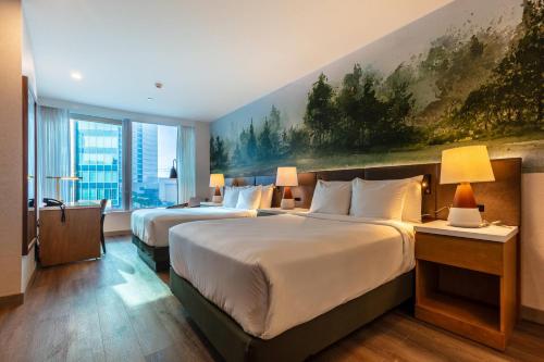 two beds in a hotel room with a painting on the wall at Radisson Hotel Trinidad in Port-of-Spain