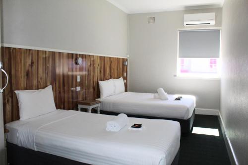 a hotel room with two beds and a window at Criterion Hotel Gundagai in Gundagai