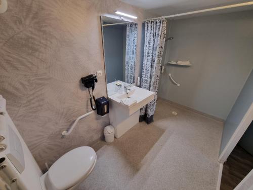 a bathroom with a white toilet and a sink at Cit'Hotel Les Atlantes Royan parking privé in Médis