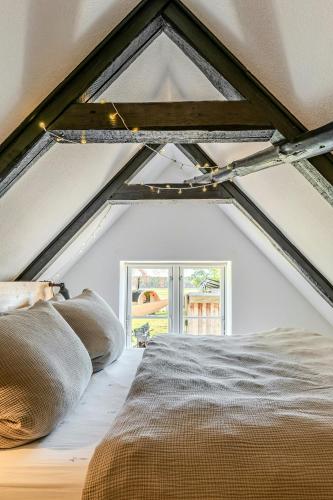 a attic bedroom with a bed and a window at Romantic Nights Under The Thatched Roof in Scharnebeck