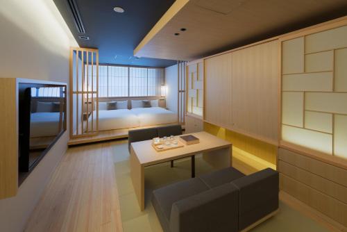京都市にあるhotel kanra kyotoのテーブル、ソファ、ベッド2台が備わる客室です。